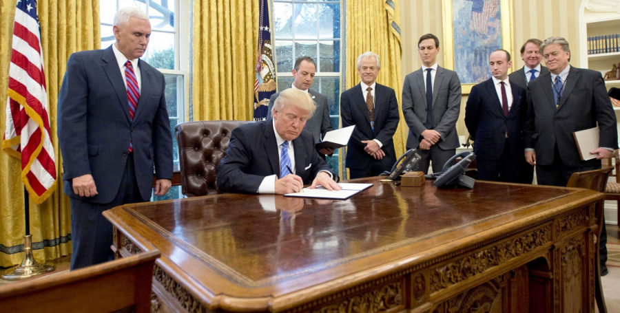 Donald Trump podpisuje dekret prezydencki otoczony swoimi doradcami. Wśród nich jest Steve Bannon (pierwszy od prawej).